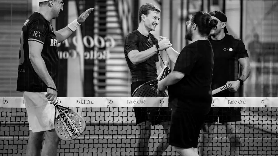 Four players shake hands and high-five across the net after a game.